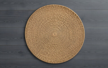 Wicker straw place mat on wooden dark background. Top view