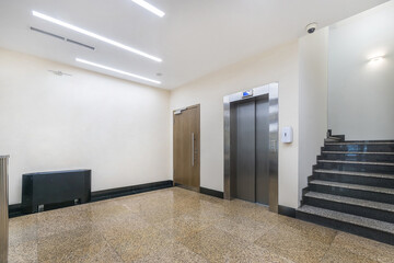 Elevator and stairs in the lobby of a public building. The wall is decorated with an abstract painting.