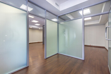 A spacious office with glass partitions and a polished wood floor. Ideal for professional .work, ready to move in immediately.
