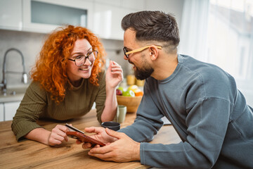 smiling couple use cellphone and credit card shopping online at kitchen