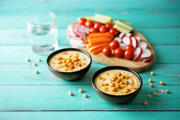 Chickpeas hummus in a bowl with fresh vegetables