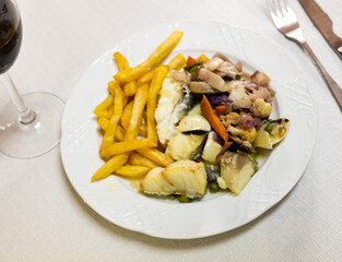Baked hake fish fillet with French fries and stewed vegetables