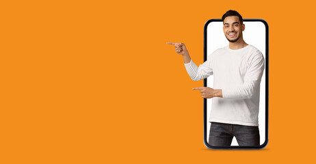 A man is actively engaging with a large smartphone screen, pointing to various applications. The vibrant background enhances the focus on technology and modern communication.