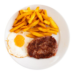 On dark tablecloth there is white plate with hearty lunch - fried flat cutlets, French fries and fried eggs. Isolated over white background