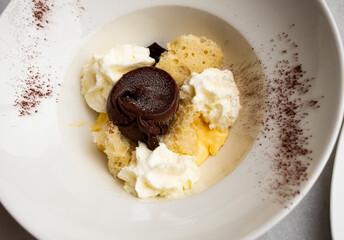 Modern interpretation of tiramisu. Airy sponge soaked in coffee, nestled with dollops of mascarpone, crowned with glossy swirl of chocolate, and kissed with cocoa powder, served in artful arrangement