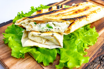 Grilled flatbread wrap filled with savory ingredients on fresh greens