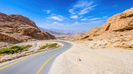 Winding desert road under blue sky with rocky landscape
