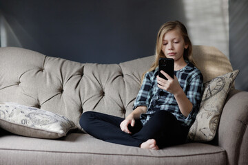 Portrait of girl Playing Game on phone. Relaxing in Living Room