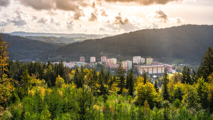 Viewing the colorful autumn landscape of Tanvald from the Spicka lookout tower, with vibrant foliage contrasting against the town's buildings and the distant mountains.