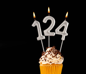 Birthday cupcake on black background - Number 124 shaped candles.