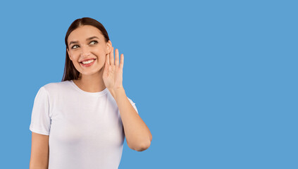 Fototapeta premium Eavesdropping Concept. Curious woman holding her hand near ear and listening carefully isolated over purple wall