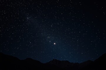 Stars twinkle brightly above mountain peaks on a clear night sky