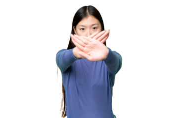 Young Asian woman over isolated chroma key background making stop gesture with her hand to stop an act