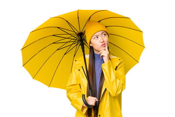 Young Asian woman with rainproof coat and umbrella over isolated chroma key background having...