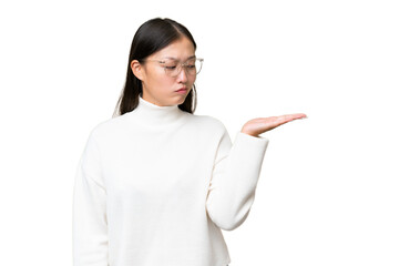 Young Asian woman over isolated background making doubts gesture