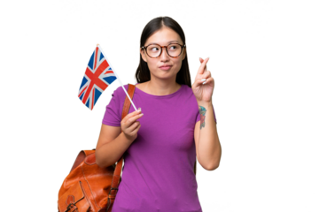 Young Asian woman holding an United Kingdom flag over isolated background with fingers crossing and wishing the best