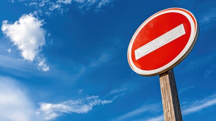 Red and white "no entry" traffic sign against blue sky background