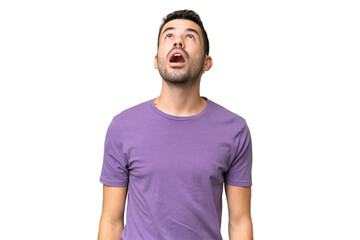 Young handsome caucasian man over isolated background looking up and with surprised expression