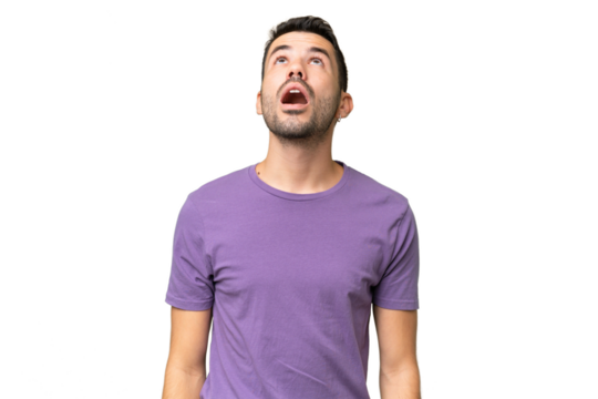 Young handsome caucasian man over isolated background looking up and with surprised expression