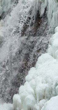 Vertical close up of a icy waterfall, river, flowing with snow and ice along each side 25 FPS Frames / Second,	Iphone 16 Pro