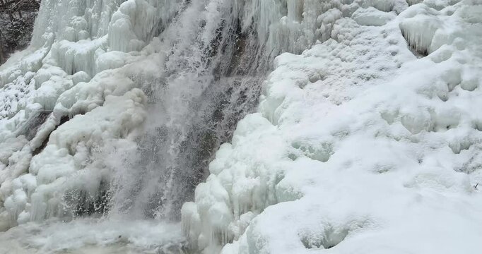 Slow motion close up of a icy waterfall, river, flowing with snow and ice along each side 25 FPS Frames / Second,	Iphone 16 Pro