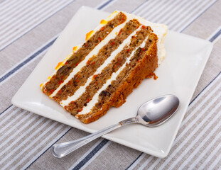 Piece of sweet carrot cake served with topping on plate
