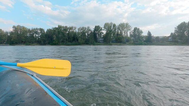 A a man paddles floaty boat in a peaceful river in a summer time. water ripple gently down to the stream. 