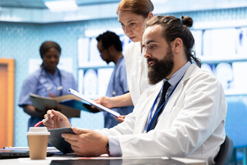 Experts team examine test results scans to develop treatment service, discussing potential diagnosis and insurance. Professional medics working together to provide medical assistance.