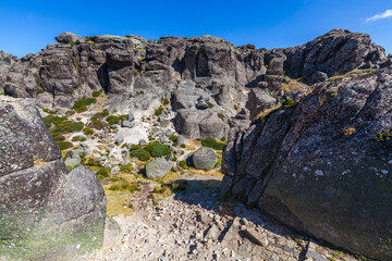 A carved image within a rock face, accessed by stone steps, creates a sense of sacred space and history against a clear blue sky