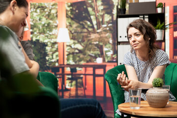 Teenage girl sitting with her mother seeks therapy for help with anxiety and emotional issues. The psychologist offers guidance on mental health and managing hormonal shifts. Family therapy.