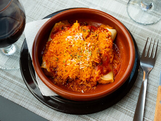 Just cooked portion of cannelloni served on table, flavored with tomato sauce and cheese.