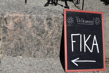 A sign for welcome fika. Written in Swedish text. Time for tea or coffee break at a cafe. Area for...