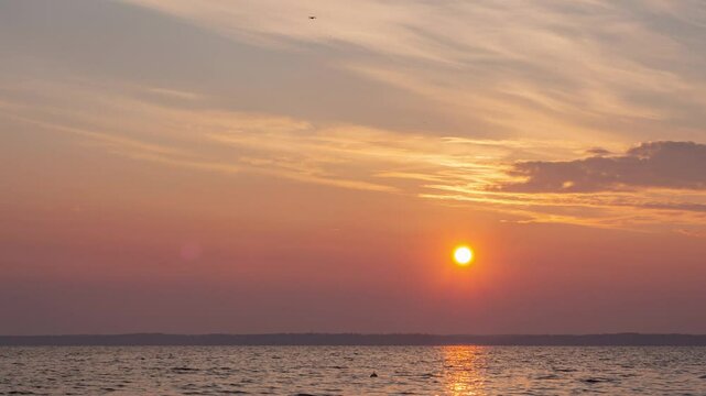 Aerial view footage B roll nature landscape background. round red sun rise up from horizontal at a peaceful sea in summer season. orange color sunset, sunrise sky reflect on water rapping gently.