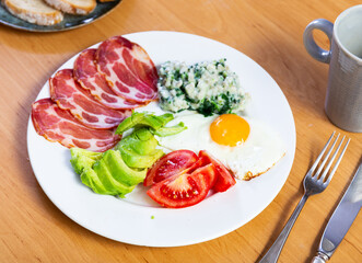 Fried egg, sliced ham, tomato, avocado and porridge served in plate for breakfast