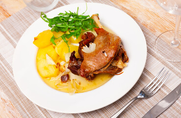 Fresh portion of confit de canard served on plate with greenery.