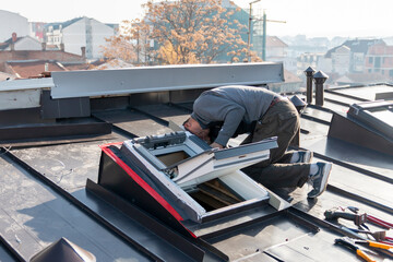 A roofer and window master work. The craftsman covers the skylight with sheet metal. Roofing tools.