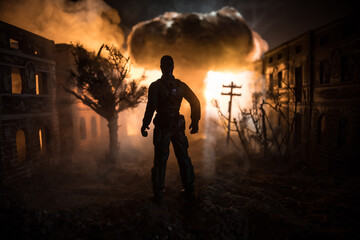 Fototapeta premium Artwork decoration. A man standing on a road of burnt up city. Apocalyptic view of city downtown as disaster film poster concept. Night scene. City destroyed by war.