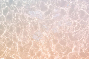 Obraz premium Crystal-clear water surface reflects sunlight creating beautiful patterns and ripples in the pool.