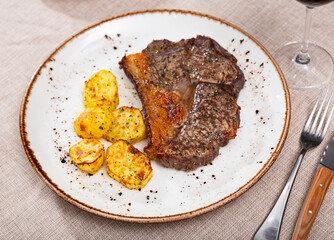 Service plate containing roast veal meat and potato with necessary table laying