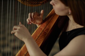 Close up on hands of professional female musician playing harp plucking strings gently performing classical music on stage, copy space