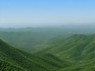 Naklejka premium Vast Green Mountain Range Stretches Across the Horizon with Clear Blue Sky Above.