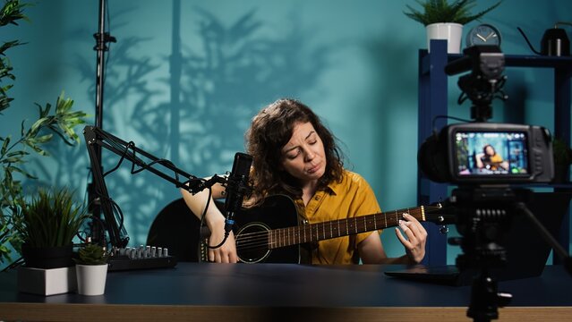 Content creator playing music on guitar during livestream with subscribers online. Skilled artist using acoustic musical instrument, doing internet concert for viewers, camera B