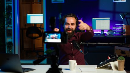 Content creator entering home studio, doing cool hand gesturing towards camera during live broadcast on online streaming platforms. Entertainer pointing fingers, captivating audience, camera A
