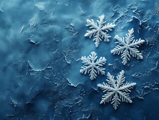 Four delicate white snowflakes are arranged on a textured blue background, creating a festive and wintery scene.