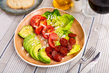 Delicious fresh lettuce salad and tomatoes served with chorizo and avocado on plate