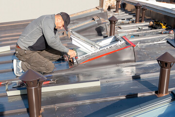 Roofer assembles sheet metal on the roof. Tinsmith worker using cordless drill screws to install...