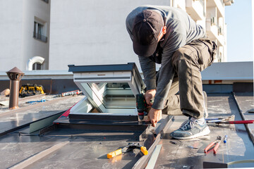 Roofer assembles sheet metal on the roof. Tinsmith worker using cordless drill screws to install new metal sheet roof.