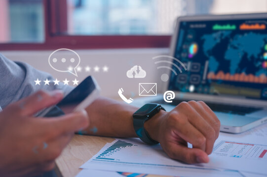 a man using a generic smartwatch with a mobile phone and computer laptop on line for searching talking check emails calling or data analysis