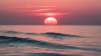 Obraz premium A breathtaking sunset over calm ocean waters, with gentle waves reflecting soft pink and orange hues in the sky.