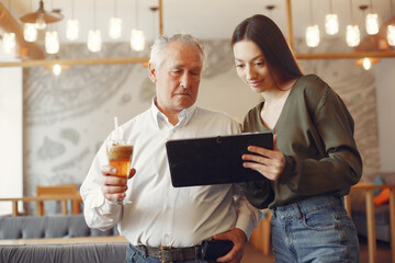 Girl teaching her grandfather how to use a tablet